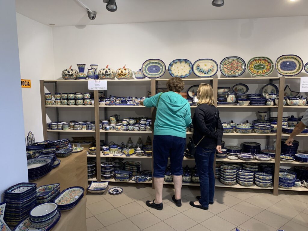 Two women looking at shelves of blue and white Boleslawiec pottery