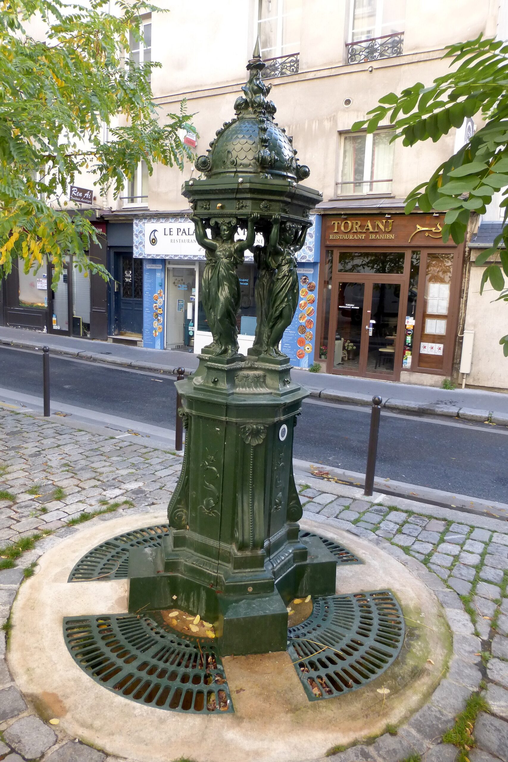 30 Free Things to Do in Paris 11 A dark green cast-iron Wallace drinking fountain on a Paris street corner