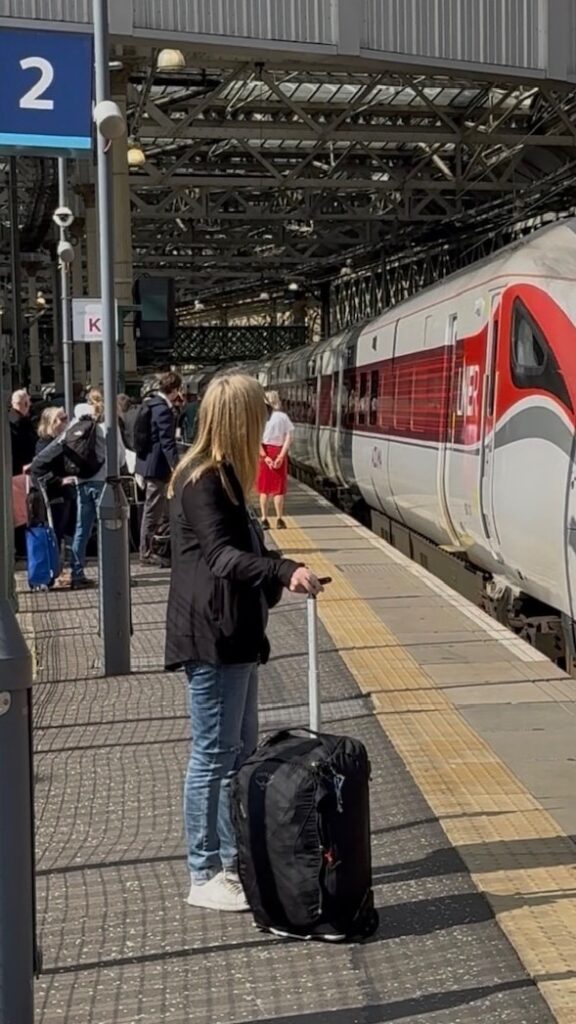 The Two Carry-On Bags I Travel With, and How to Pick Yours 2 Lisa with her black Osprey carry-on waiting on a train platform