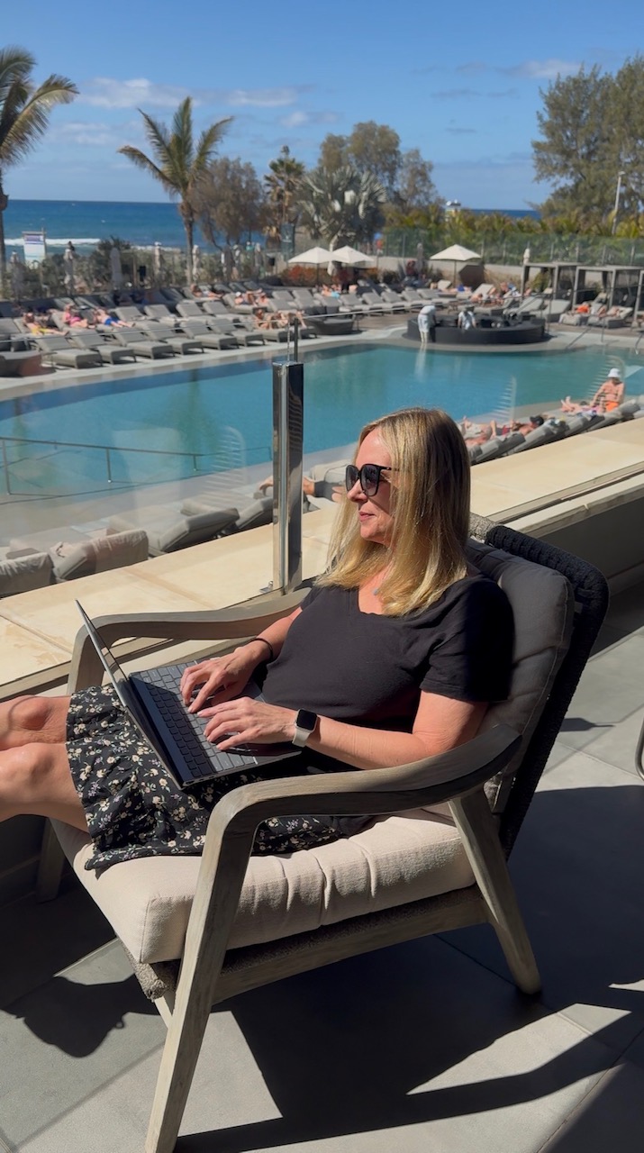 Lisa Reidmiller with a laptop on a lounger beside a pool