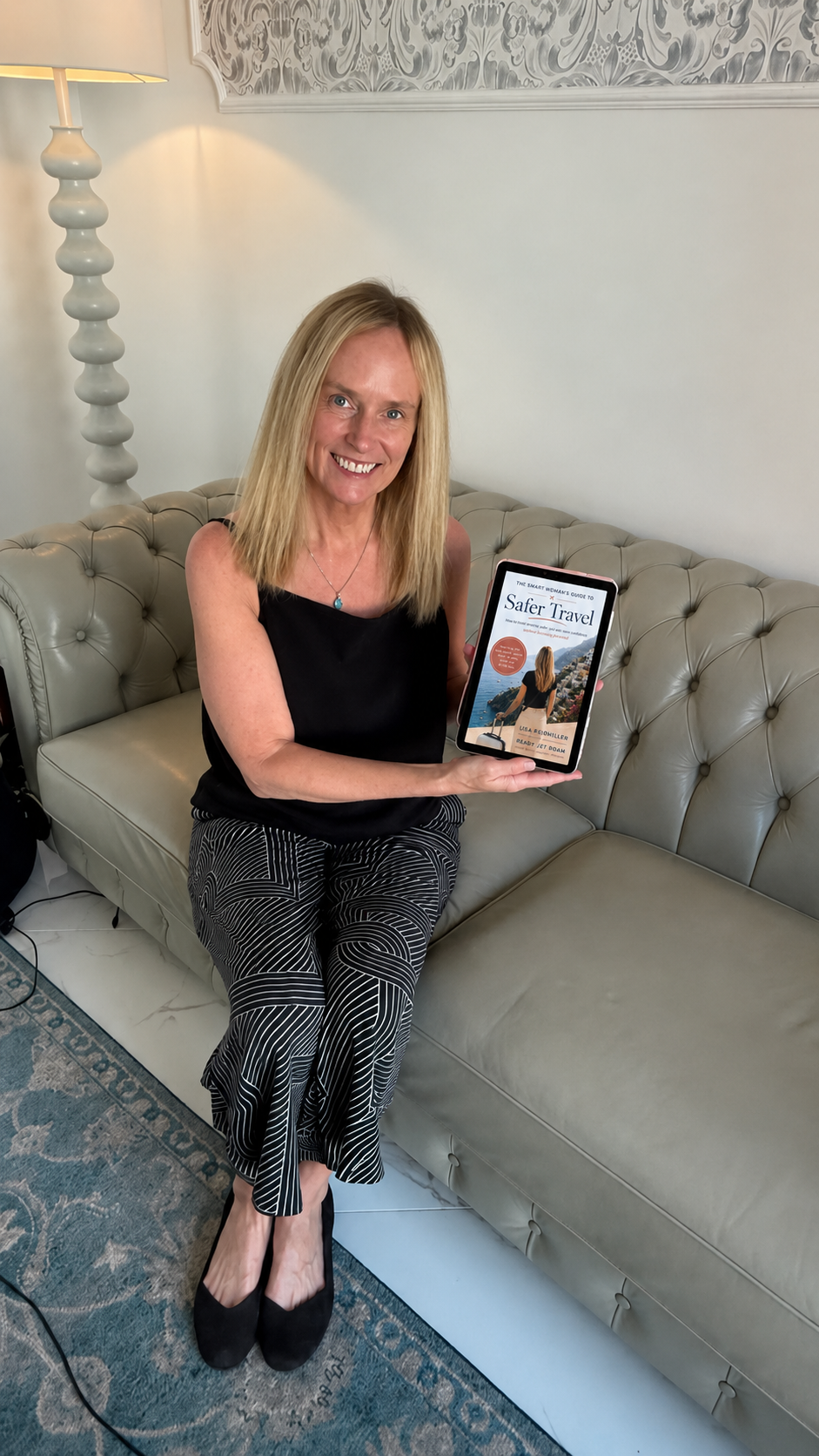 Lisa Reidmiller holding a tablet showing the cover of The Smart Woman's Guide to Safer Travel